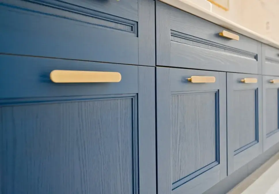 Close-up of professionally painted blue kitchen cabinets with golden handles