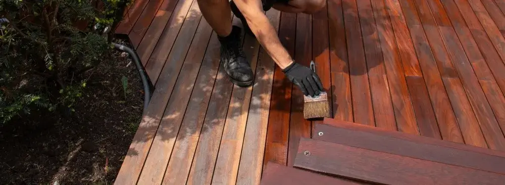 Professional applying stain to a wooden outdoor deck