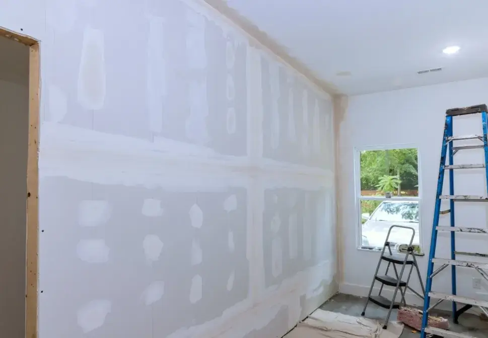 Drywall under repair and preparation for interior painting with ladders and tools