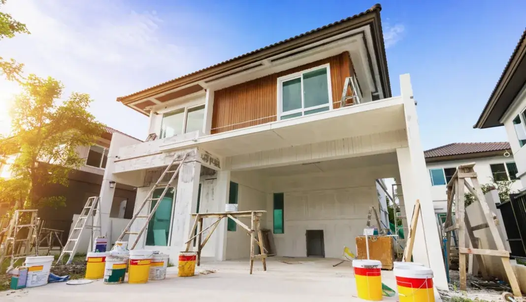 Residential home exterior being painted with ladders and paint buckets