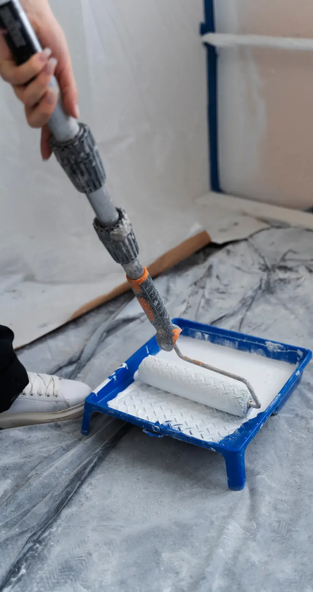 Close-up of a paint roller dipped in white paint during interior wall painting