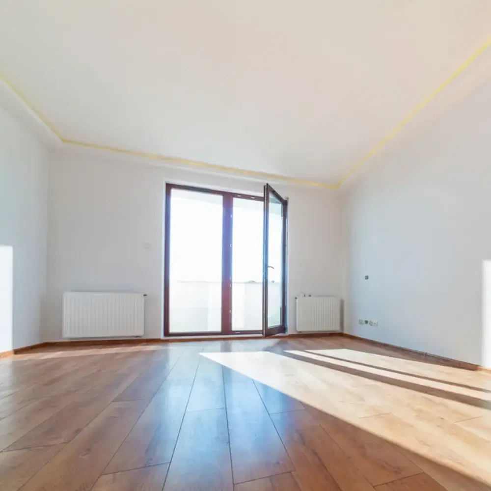 Bright empty living room with wood flooring and freshly painted white walls