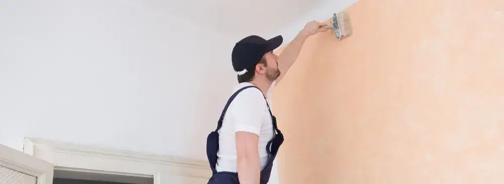 Painter brushing soft pastel color on interior wall