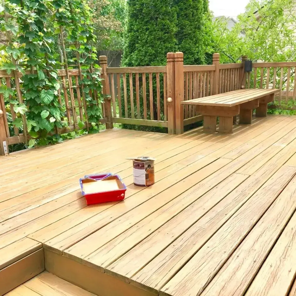 Freshly painted wooden deck with bench in a lush backyard